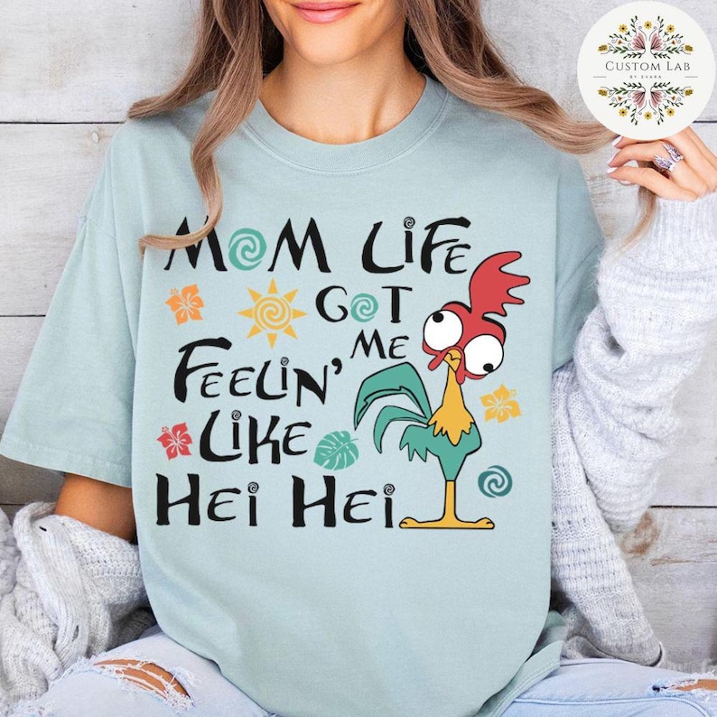May include: Light blue t-shirt with a cartoon rooster and the text "Mom Life Got Me Feelin' Like Hei Hei".