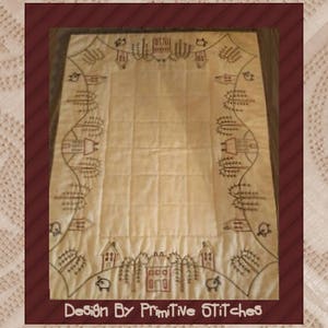 May include: A cream-colored quilted fabric with a brown embroidered design of houses and trees around the border. The text "Design By Primitive Stitches" is at the bottom of the fabric.