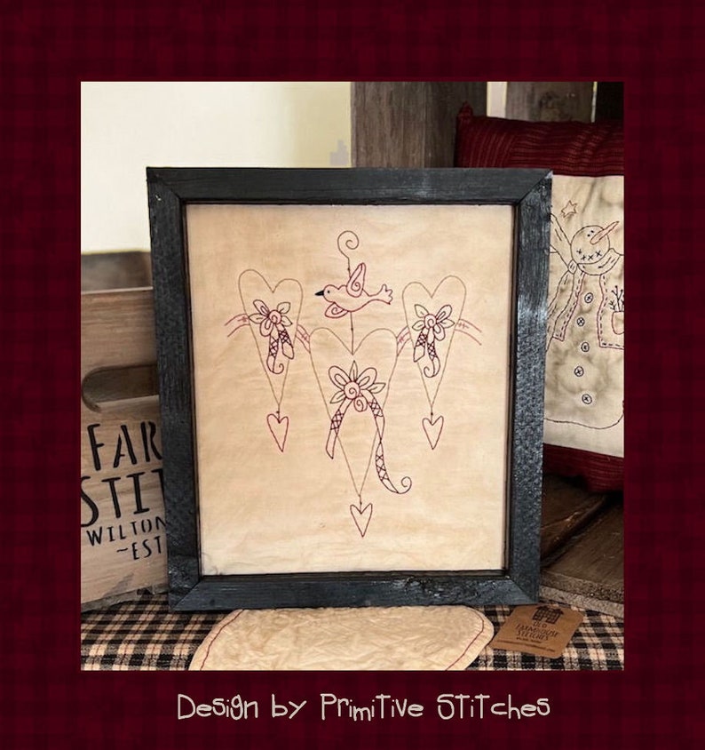 Peut inclure: Une &oelig;uvre d'art encadr&eacute;e avec un motif de c&oelig;urs, un oiseau et des d&eacute;tails floraux. L'&oelig;uvre, dans un cadre noir, a une esth&eacute;tique rustique et vintage. Le texte "Design by Primitive STitcHeS" est en bas.