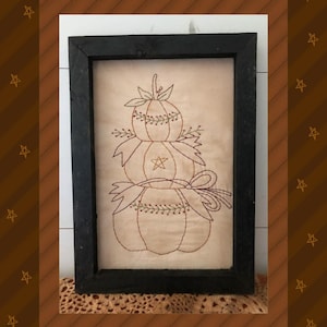 Puede incluir: Un diseño de bordado enmarcado de tres calabazas apiladas en un esquema de color marrón y verde. Las calabazas están cosidas con un contorno simple y tienen un aspecto rústico y vintage. El diseño se titula "Design by Primitive Stitches".