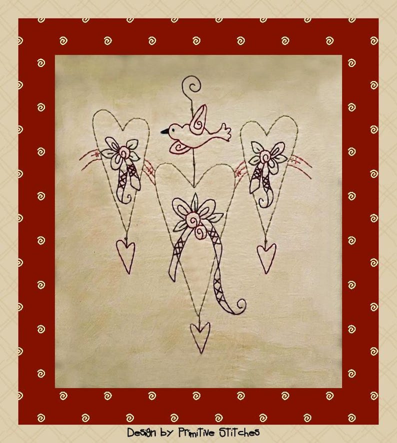 Peut inclure: Broderie encadr&eacute;e avec un motif central en forme de lustre en c&oelig;ur, orn&eacute; d'un oiseau et de motifs floraux. Le dessin est r&eacute;alis&eacute; en fil noir sur fond cr&egrave;me, encadr&eacute; d'une bordure rouge avec des volutes d&eacute;coratives. Le texte "Design by Primitive Stitches" est en bas.