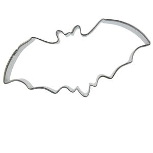 Puede incluir: Un cortador de galletas de metal plateado con forma de murciélago. El cortador está diseñado para hacer galletas con temática de Halloween.