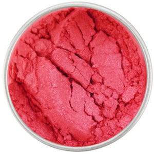 Può includere: Primo piano di un piccolo contenitore rotondo pieno di una polvere rosa brillante e scintillante. La polvere è sciolta e ha un aspetto leggermente strutturato.