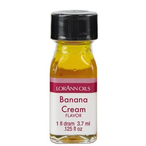 Puede incluir: Una pequeña botella de vidrio con una tapa negra llena de un líquido amarillo. La etiqueta dice "Lorann Oils Banana Cream Flavor 1 fl dram 3.7 ml .125 fl oz"