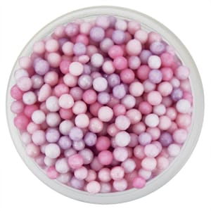 Könnte beinhalten: Ein klares Glasgefäß gefüllt mit kleinen, runden, pastellfarbenen Streuseln. Die Streusel sind eine Mischung aus Rosa, Lavendel und Weiß, wodurch ein weiches, farbenfrohes Aussehen entsteht. Das Glas steht vor einem weißen Hintergrund.
