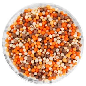 May include: A glass bowl filled with a variety of small, round sprinkles in shades of orange, brown, and beige.