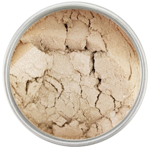 May include: A close-up view of a round container filled with a light beige powder with a shimmery finish. The powder is slightly cracked and has a textured surface.