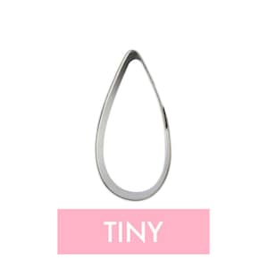 May include: A silver metal cookie cutter shaped like a teardrop. The cutter is labeled "TINY" in pink.