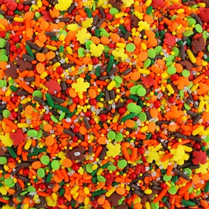 Puede incluir: Una mezcla de chispas coloridas en colores otoñales, incluyendo naranja, amarillo, verde, marrón y rojo. Las chispas tienen forma de estrellas, hojas y pequeñas bolas.