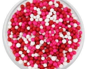 May include: A clear, round container filled with colorful sprinkles. The sprinkles are small, round, and in shades of red, pink, and white. The sprinkles are densely packed, creating a vibrant and textured appearance.