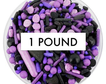 May include: One pound of purple and black sprinkles in a clear plastic container. The sprinkles are a mix of different shapes and sizes, including stars, hearts, and dots. The container has a white label that says "1 POUND".