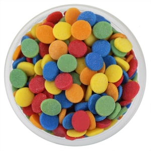 May include: A clear glass container filled with colorful, round sprinkles. The sprinkles are in various colors, including red, orange, yellow, green, and blue. The sprinkles are small and evenly distributed throughout the container, creating a vibrant and playful appearance.