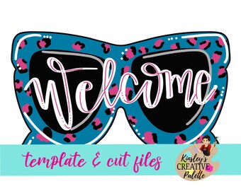 Op de afbeelding: Een tealblauwe zonnebril met een roze luipaardprint. De zonnebril heeft zwarte glazen en het woord "welcome" staat in wit met roze accenten.