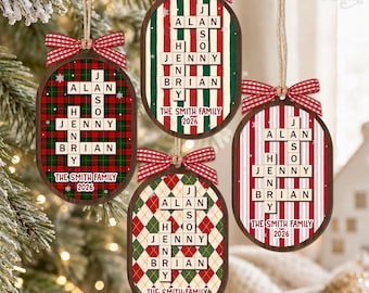 May include: Four oval-shaped wooden Christmas ornaments featuring a crossword-style grid of names including Alan, Jason, Jenny, Henry, and Brian. Each ornament displays The Smith Family 2026 and is topped with a red and white gingham bow.