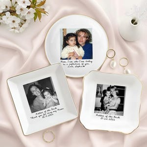 May include: Three white ceramic trinket dishes with gold-toned rims, each featuring a personalized black and white photograph and handwritten-style text. One round dish and two square dishes display family photos with dates and messages.