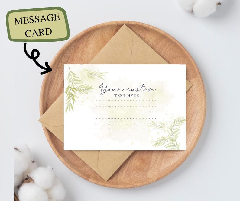 May include: A white message card with green watercolor leaves and the text "Your custom text here" sits on a wooden plate with a brown envelope. The card is labeled "MESSAGE CARD" in a green box.
