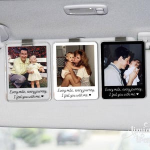 May include: Three rectangular car visor clips featuring personal photographs of people and children. Each clip displays the printed text: Every mile, every journey, I feel you with me, accompanied by a small heart symbol at the bottom of the frame.