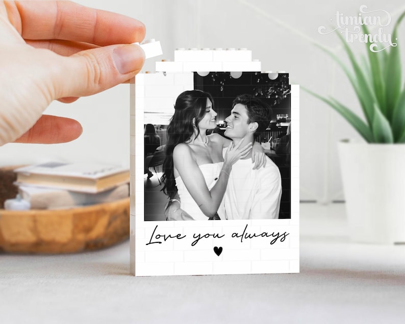 Puede incluir: Un marco rectangular de bloques de construcci&oacute;n blancos con una fotograf&iacute;a en blanco y negro de una pareja abraz&aacute;ndose. El texto Love you always est&aacute; impreso en letra cursiva negra debajo de la foto, seguido de un peque&ntilde;o coraz&oacute;n negro en el centro.