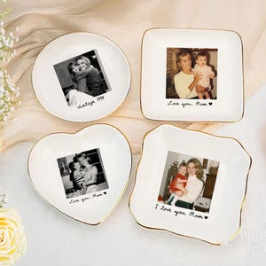 May include: Four white ceramic trinket dishes with gold-painted rims, each featuring a custom black and white photograph in the center. The dishes are round, square, heart-shaped, and square with wavy edges, each inscribed with handwritten text.