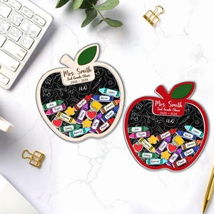 May include: Two apple-shaped teacher gifts with a chalkboard design. The gifts are personalized for "Mrs. Smith, 3rd Grade Class 2025-2026." Each apple features colorful crayon and star accents with student names. One apple is red, the other is natural wood.