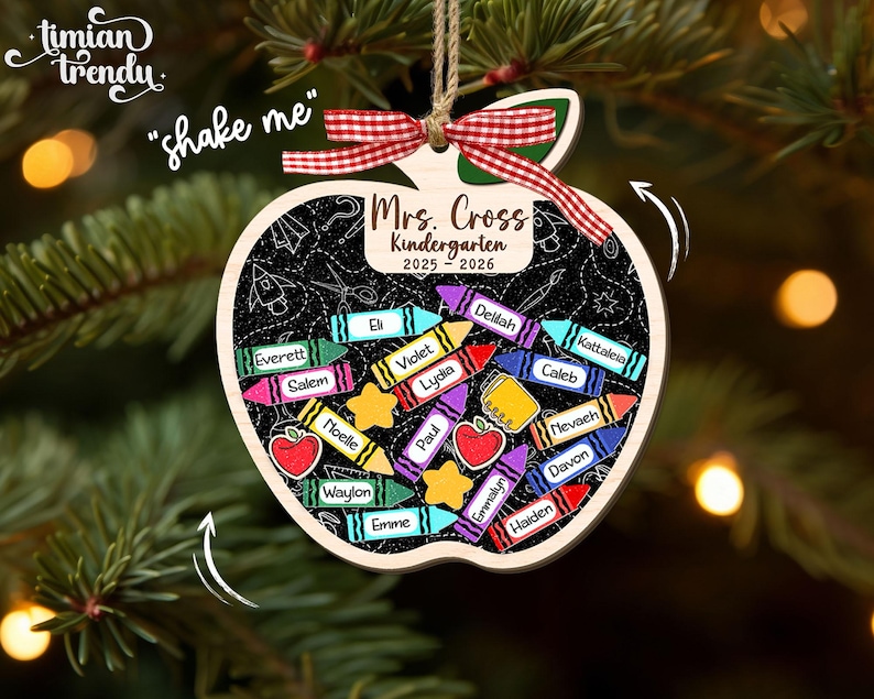 May include: Wooden apple-shaped ornament with a chalkboard design. The ornament features the text "Mrs. Cross Kindergarten 2025-2026" and includes colorful crayon and apple illustrations. It is decorated with a red and white ribbon and a jute string for hanging.
