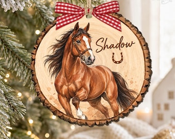 May include: A round wooden ornament with bark edges featuring a brown horse illustration, the name Shadow, and a horseshoe icon. A red and white gingham ribbon bow is tied at the top with a jute twine loop for hanging on a tree branch.