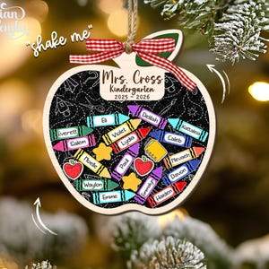 May include: Wooden apple-shaped ornament with a chalkboard design. It features the text "Mrs. Cross Kindergarten 2025-2026" and student names on colorful crayon illustrations. A red and white ribbon is attached for hanging.