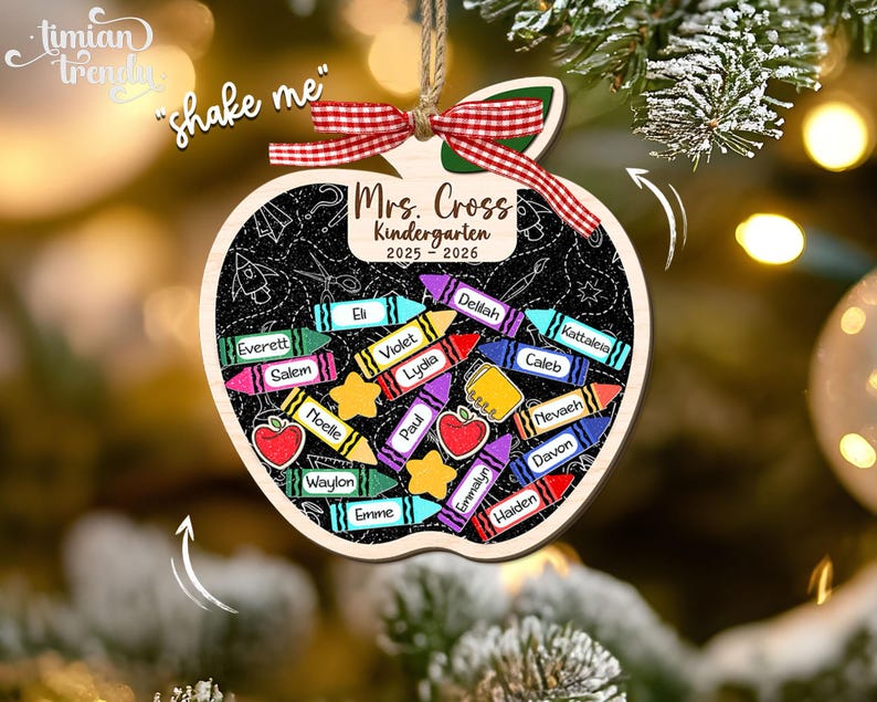 May include: Wooden apple-shaped ornament with a chalkboard design. It features the text "Mrs. Cross Kindergarten 2025-2026" and student names on colorful crayon illustrations. A red and white ribbon is attached for hanging.