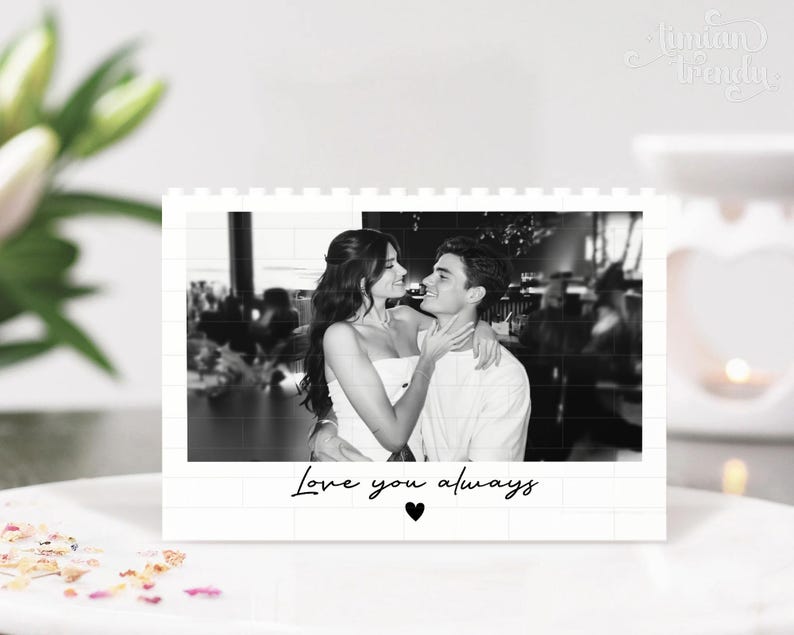 Puede incluir: Un expositor rectangular blanco con una fotograf&iacute;a en blanco y negro de dos personas abrazadas. El texto "Love you always" est&aacute; impreso en letra cursiva negra debajo de la foto, acompa&ntilde;ado de un peque&ntilde;o icono de coraz&oacute;n negro centrado.