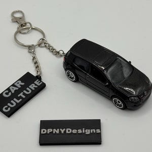 May include: Black diecast car keyring with a silver chain and a black tag that says "CAR CULTURE". A small black tag at the bottom says "DPNYDesigns".