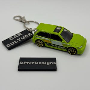 Könnte beinhalten: Ein hellgrüner Honda Civic Spielzeugauto-Schlüsselanhänger mit goldenen Felgen und einem schwarzen Anhänger mit der Aufschrift "CAR CULTURE". Der Schlüsselanhänger hat auch einen schwarzen Anhänger mit der Aufschrift "DPNYDesigns".