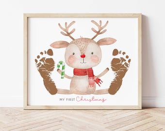 May include: A watercolor illustration of a reindeer with a red scarf and candy cane. Two brown footprints are on either side of the reindeer. The text "My First Christmas" is below the reindeer.