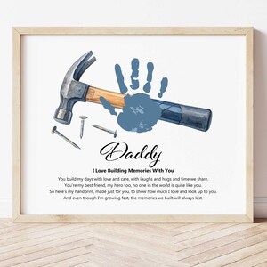 May include: Framed print featuring a watercolor illustration of a hammer, nails, and a blue handprint. The word "Daddy" is written in elegant script, with the text "I Love Building Memories With You" below. A heartfelt message is included.