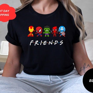 Puede incluir: Camiseta negra con un gr&aacute;fico de superh&eacute;roes de dibujos animados, incluyendo Spider-Man, Hulk, Iron Man, Deadpool y Capit&aacute;n Am&eacute;rica. El texto "FRIENDS" est&aacute; debajo de los personajes.