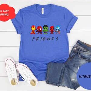Puede incluir: Una camiseta azul con un gr&aacute;fico del logotipo de "Friends" y superh&eacute;roes de dibujos animados. Los superh&eacute;roes son Iron Man, Spiderman, Hulk, Thor y Captain America. El texto "FRIENDS" est&aacute; debajo de los superh&eacute;roes.