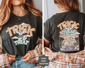 May include: Dark grey heather t-shirt with a Halloween graphic. The front displays "Trick or Treat" with a cartoon character. The back of the shirt also has a Halloween graphic with the words "Trick Treat".
