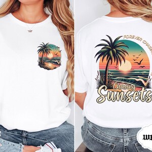 May include: White t-shirt with a colorful sunset graphic. The front features a small design of a palm tree, ocean, and sunset. The back has a larger design with the text "Forever Chasing Sunsets" and "Chasing Sunsets".