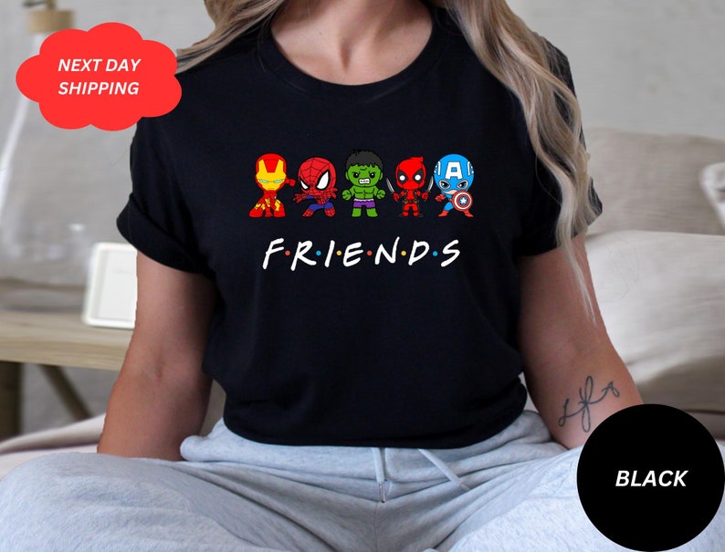 Puede incluir: Camiseta negra con un gr&aacute;fico de superh&eacute;roes de dibujos animados, incluyendo Spider-Man, Hulk, Iron Man, Deadpool y Capit&aacute;n Am&eacute;rica. El texto "FRIENDS" est&aacute; debajo de los personajes.