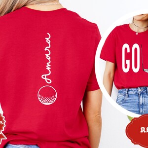 May include: Red t-shirts with golf-themed designs. One shirt features the word "GOLF" with a golf club and ball graphic. The other shirt has the name "Amara" and a golf ball graphic.