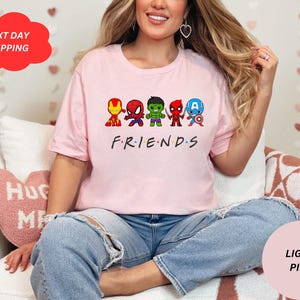 Puede incluir: Una camiseta rosa claro con un gr&aacute;fico de superh&eacute;roes de dibujos animados. El texto "FRIENDS" est&aacute; impreso debajo del gr&aacute;fico.