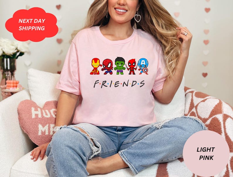 Puede incluir: Una camiseta rosa claro con un gr&aacute;fico de superh&eacute;roes de dibujos animados. El texto "FRIENDS" est&aacute; impreso debajo del gr&aacute;fico.