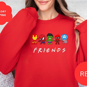 Pu&ograve; includere: Felpa rossa con una grafica del logo "Friends" che presenta versioni cartoon di Iron Man, Spiderman, Hulk, Deadpool e Captain America. Il testo "FRIENDS" &egrave; sotto i personaggi.