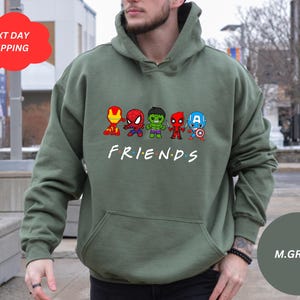 Pu&ograve; includere: Felpa con cappuccio verde con una grafica dei personaggi degli Avengers, Iron Man, Spider-Man, Hulk e Captain America, in fila con la parola "FRIENDS" sotto.