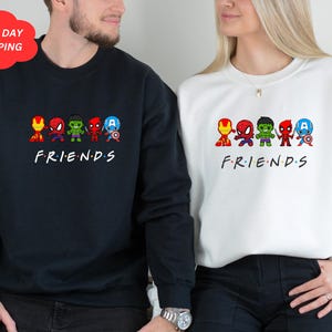 Pu&ograve; includere: Una coppia di felpe nere e bianche con una grafica di supereroi dei cartoni animati e la parola "FRIENDS" stampata sul davanti.