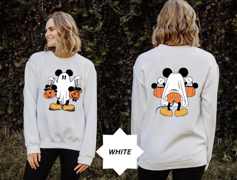 May include: White sweatshirt featuring a Halloween-themed Mickey Mouse design. The front graphic shows Mickey as a ghost holding jack-o'-lanterns. The back graphic shows Mickey Mouse with a ghost sheet and pumpkins. The word "WHITE" is in a white starburst.