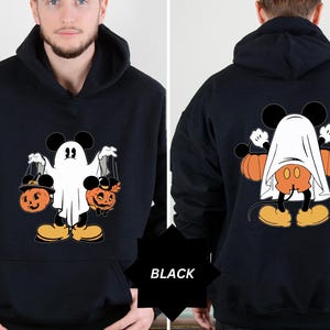 May include: Black Halloween hoodie featuring a cartoon character dressed as a ghost, holding pumpkin-shaped treat bags. The design includes orange pumpkins and the text "BLACK". The back of the hoodie shows the character with pumpkins.
