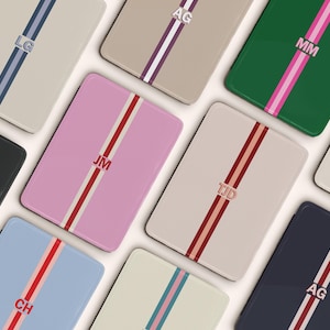 May include: A collection of personalized phone cases in various colors, each featuring a vertical stripe design with initials. Colors include pink, green, black, blue, and beige. The cases have a glossy finish and a rectangular shape.