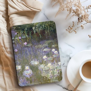 Może przedstawiać: Etui na tablet z obrazem w stylu Moneta przedstawiającym lilie wodne w stawie, w odcieniach zieleni, fioletu i bieli. Na marmurowej powierzchni, obok filiżanki kawy i suszonych kwiat&oacute;w.