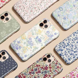 May include: A collection of floral patterned phone cases in various colors, including green, blue, and pink. The cases feature a glossy finish and are arranged on a neutral background. The designs showcase a variety of flower patterns.