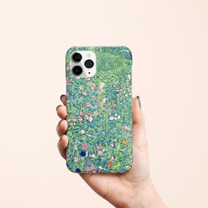 May include: A phone case featuring a floral design with a green background and colorful flowers. The case has a glossy finish and a camera cutout. The design is reminiscent of a painting.